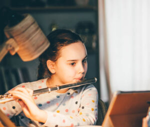 Child proudly leaning to play an instrument, flute