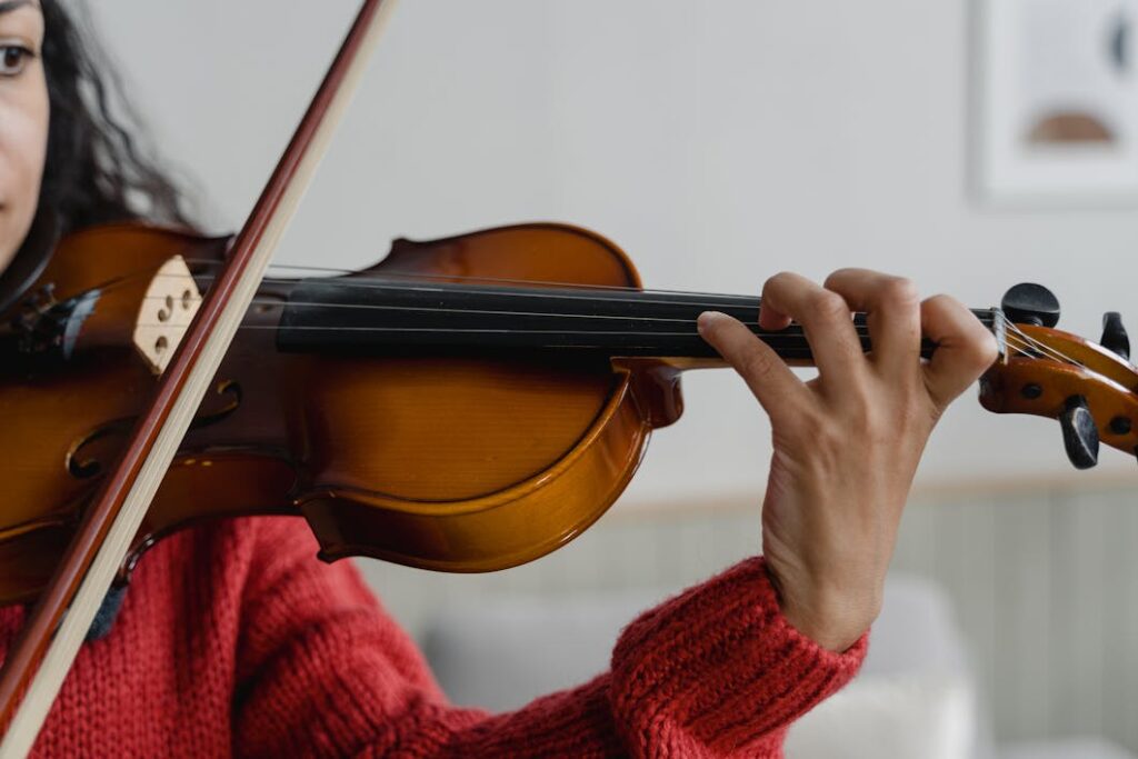 Person in Red Knitted Sweater Playing Violin.Adult Music Lessons